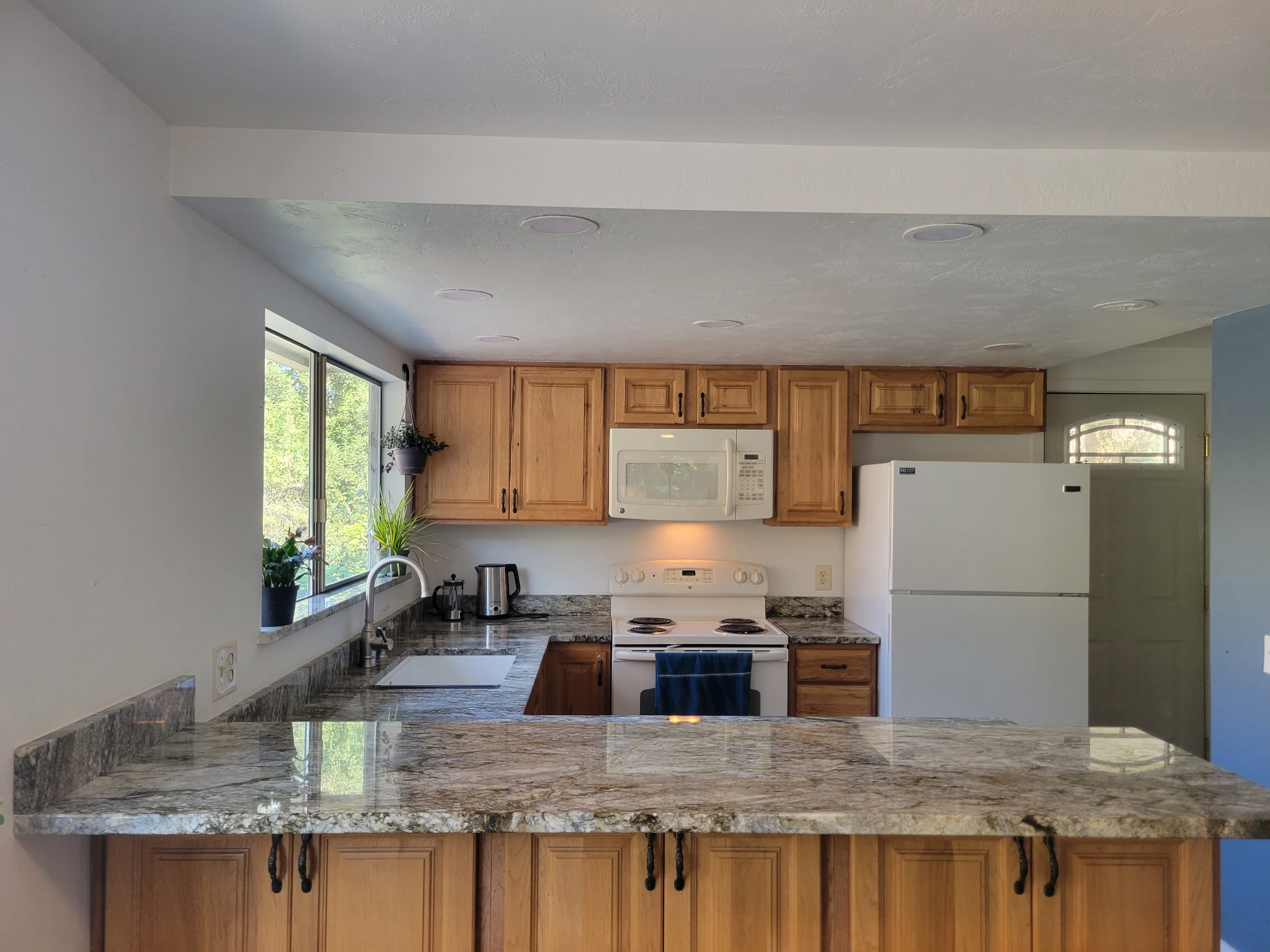 Completed kitchen renovation with wood cabinetry and stone counters