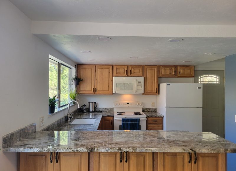 Completed kitchen renovation with wood cabinetry and stone counters