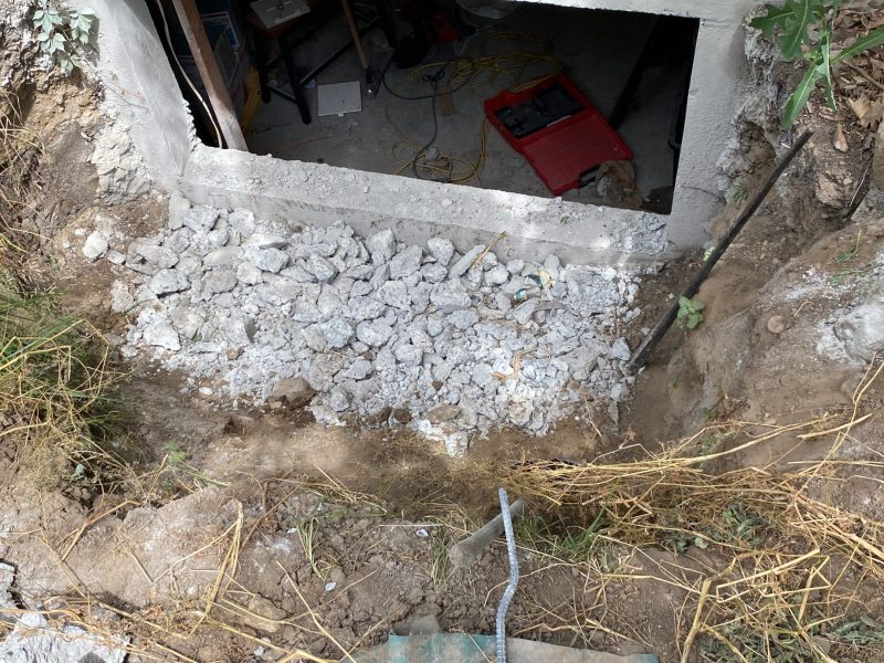 Below-grade excavation and masonry preparation outside a home